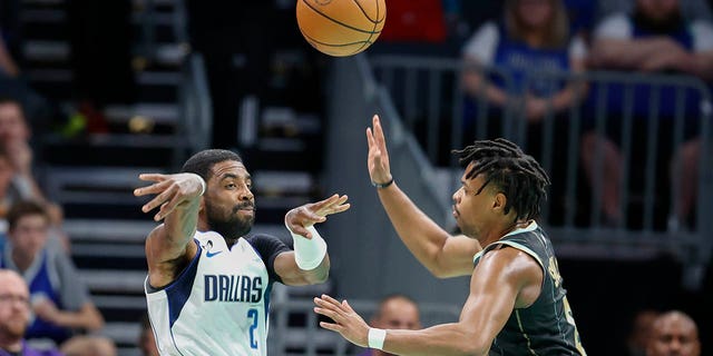 Dallas Mavericks guard Kyrie Irving passes against Hornets guard Dennis Smith Jr. in Charlotte, Sunday, March 26, 2023.
