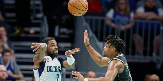 Dallas Mavericks guard Kyrie Irving passes against Hornets guard Dennis Smith Jr. in Charlotte, Sunday, March 26, 2023.