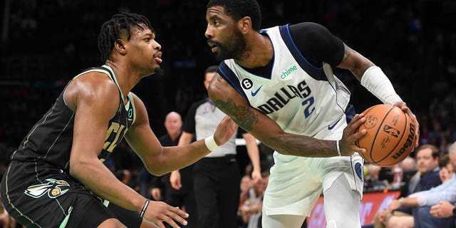 Dallas Mavericks guard Kyrie Irving is defended by Hornets guard Dennis Smith Jr. at the Spectrum Center in Charlotte, March 26, 2023.