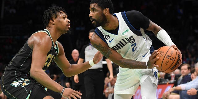 Dallas Mavericks guard Kyrie Irving is defended by Hornets guard Dennis Smith Jr. at the Spectrum Center in Charlotte on March 26, 2023.