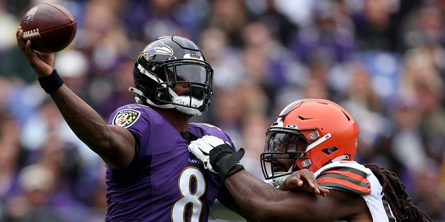 Quarterback Lamar Jackson, #8 of the Baltimore Ravens, gets off a pass while being pressured by defensive end Jadeveon Clowney, #90 of the Cleveland Browns, in the first half at M&amp;T Bank Stadium on Oct. 23, 2022 in Baltimore.