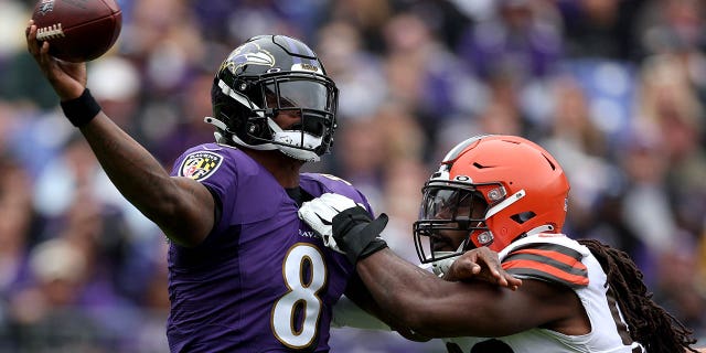 Quarterback Lamar Jackson, #8 of the Baltimore Ravens, gets off a pass while being pressured by defensive end Jadeveon Clowney, #90 of the Cleveland Browns, in the first half at M&amp;T Bank Stadium on Oct. 23, 2022 in Baltimore.