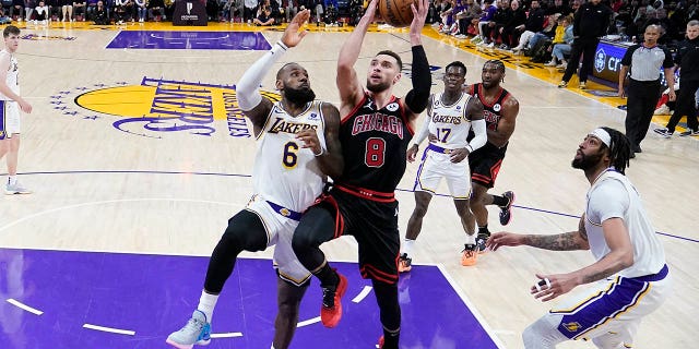 Chicago Bulls guard Zach LaVine, #8, drives to the basket between Los Angeles Lakers forward LeBron James, left, and forward Anthony Davis during the second half of an NBA basketball game, Sunday, March 26, 2023, in Los Angeles.