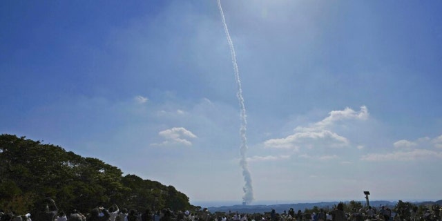 Les gens regardent le lancement d'une fusée H3, dans un champ de la ville de Minamitane à Kagoshima, dans le sud du Japon, le mardi 7 mars 2023.