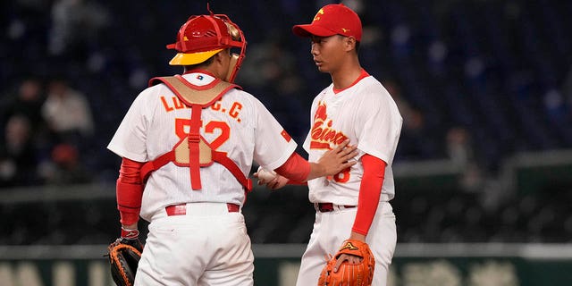 Luan Chenchen, a la izquierda, habla con Sun Hailing en el montículo durante la cuarta entrada del partido de primera ronda del Grupo B entre Corea del Sur y China en el Clásico Mundial de Béisbol en el Tokyo Dome en Tokio el lunes 13 de marzo de 2023.
