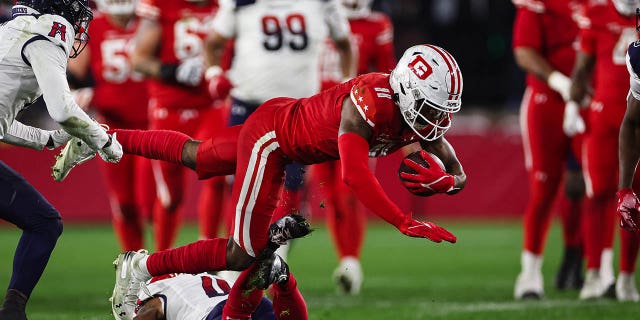 Lucky Jackson, #11 of the DC Defenders, dives over William Likely #4 of the Houston Roughnecks during the first half of the XFL game at Audi Field on March 27, 2023 in Washington, D.C.