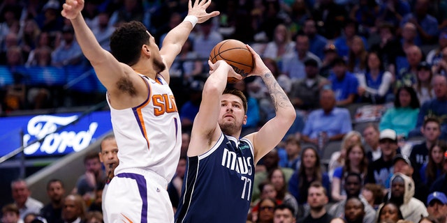 Luka Doncic #77 de los Dallas Mavericks atrapa el balón mientras Devin Booker #1 de los Phoenix Suns corre en la primera mitad del juego en el American Airlines Center el 5 de marzo de 2023 en Dallas, Texas.