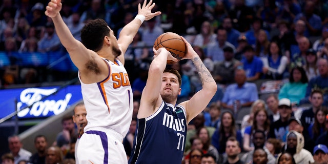 Luka Doncic #77 of the Dallas Mavericks shoots the ball as Devin Booker #1 of the Phoenix Suns defends in the first half of the game at American Airlines Center on March 5, 2023 in Dallas, Texas.