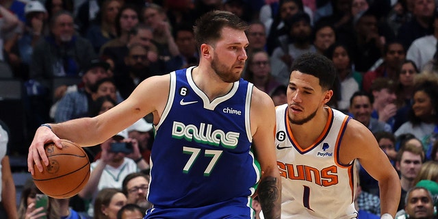 Luka Doncic #77 of the Dallas Mavericks is guarded by Devin Booker #1 of the Phoenix Suns in the second half at American Airlines Center on December 05, 2022 in Dallas, Texas.