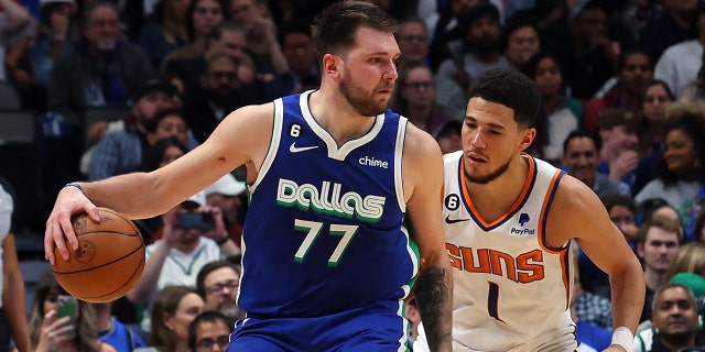 Luka Doncic #77 of the Dallas Mavericks is defended by Devin Booker #1 of the Phoenix Suns in the second half at the American Airlines Center on December 5, 2022 in Dallas, Texas.