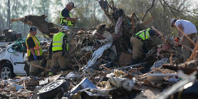 Emergency rescuers and first responders climb through a tornado-ravaged mobile home park in search of bodies that may be buried in piles of debris, insulation and home furnishings Saturday morning in Rolling Fork, Miss.