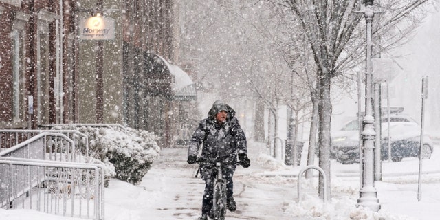 Corey Baird rides his knobby-tired mountain bike on a slippery sidewalk while peddling to a grocery store during a heavy snowfall, Tuesday, March 14, 2023, in Brunswick, Maine. 