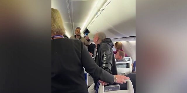 The man in the sports jacket is seen confronting the heavily tattooed man and other passengers. A Southwest Airlines flight attendant is seen standing between the two men.