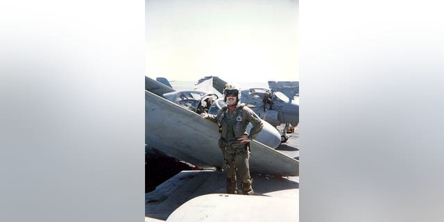 O piloto do A-6 Intruder da Marinha, Jim Seaman, apoiou-se na asa de seu jato.  Seaman faz parte de um grupo de pilotos que morreram de câncer.