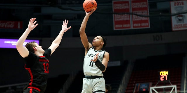 Jordan Gainey (11) of the USC Upstate Spartans shoots the ball over Lucas Stieber (13) of the Gardner-Webb Runnin' Bulldogs during the Big South Tournament March 3, 2023, at Bojangles Coliseum in Charlotte, N.C.