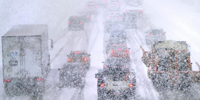 Plows, at right, try to pass nearly stopped traffic, due to weather conditions, on Route 93 South, Tuesday, March 14, 2023, in Londonderry, New Hampshire. 