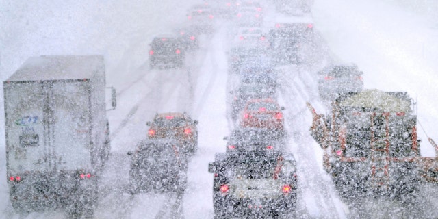 Plows, at right, try to pass nearly stopped traffic, due to weather conditions, on Route 93 South, Tuesday, March 14, 2023, in Londonderry, New Hampshire.