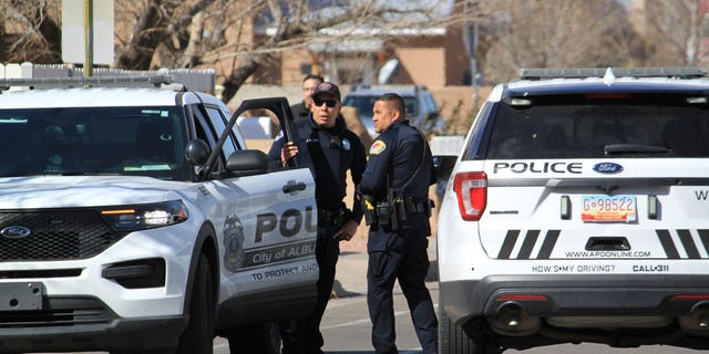 Police work outside a home on Feb. 23, 2023, in Albuquerque, N.M., where they found two people stabbed and another person dead of a self-inflicted gunshot wound.