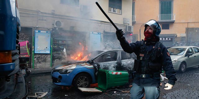 A police car burns during clashes with supporters of the Eitracht Frankfurt soccer team Wednesday, March 15, 2023 in Naples, Italy, where their team is about to play a Champions League, round of 16, second leg soccer match against Naples.