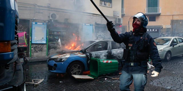 A police car burns during clashes with supporters of the Eitracht Frankfurt soccer team Wednesday, March 15, 2023 in Naples, Italy, where their team is about to play a Champions League, round of 16, second leg soccer match against Naples.