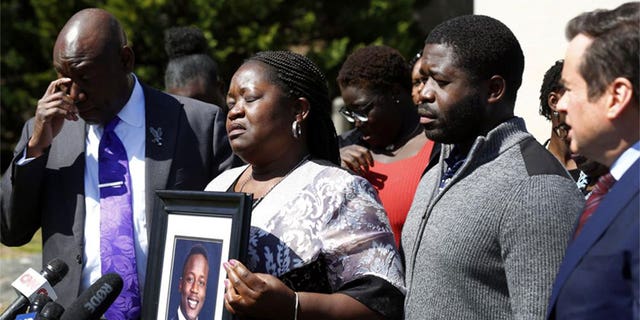 Caroline Ouko, mother of Irvo Otieno, holds a portrait of her son with attorney Ben Crump, left, her older son, Leon Ochieng and attorney Mark Krudys at the Dinwiddie Courthouse in Dinwiddie, Va., on Thursday, March 16, 2023. There is goodness in his music and that's all I'm left with now — he's gone," Otieno's mother, Caroline Ouko, said at the news conference while clutching a framed photo of her son. 