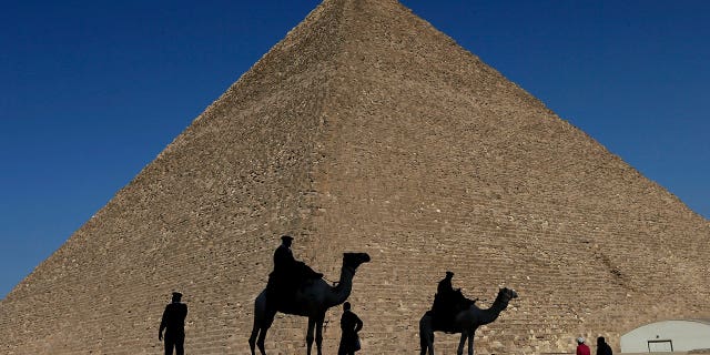 Policemen are silhouetted against the Great Pyramid of Giza, Egypt, on Dec 12, 2012. Egypt unveiled on March 2, 2023, the discovery of a 30-foot-long chamber inside the pyramid.