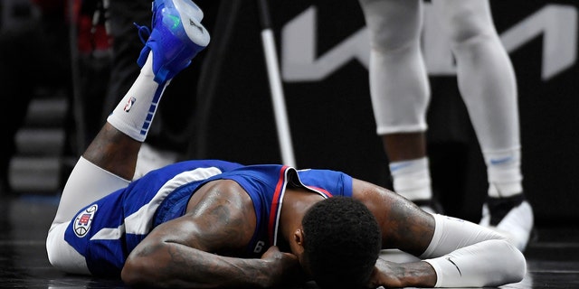 Paul George #13 of the Los Angeles Clippers lies on the ground after injuring his right knee on a foul by Oklahoma City Thunder's Luguentz Dort in the second half at Crypto.com Arena on March 21, 2023 in Los Angeles, California.