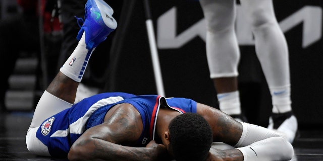 Paul George #13 of the Los Angeles Clippers lies on the floor after injuring his right knee on a foul by Luguentz Dort of the Oklahoma City Thunder in the second half at Crypto.com Arena on March 21, 2023 in Los Angeles, California.