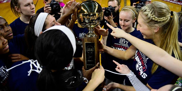 El equipo de baloncesto femenino de los cuáqueros de Pensilvania toca el trofeo del campeonato después de derrotar a los Tigres de Princeton en la final del campeonato de la Ivy League en Palestra el 12 de marzo de 2017 en Filadelfia.