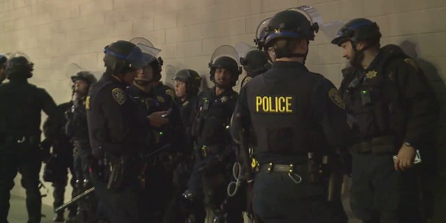 Law enforcement officers stop unrest outside a venue at UC Davis where protesters attempted to stop a speaking event. 