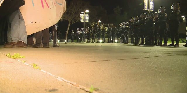 A line of police officers stop protesters from entering the University Credit Union Center at UC Davis, on March 14, 2023.