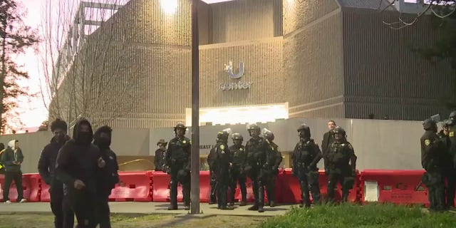 Protesters and law enforcement officers surround the University Credit Union Center on March 14, 2023.