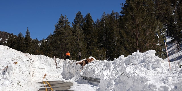 Caltrans workers inspect the damage caused by an avalanche on California State Route 38 after a series of snow storms on March 2, 2023, near Big Bear, California. 