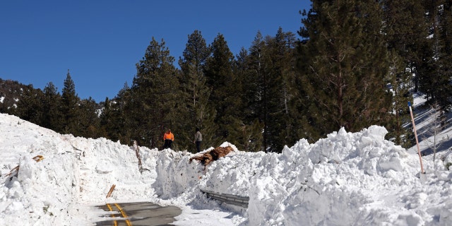 Caltrans workers inspect the damage caused by an avalanche on California State Route 38 after a series of snow storms on March 2, 2023, near Big Bear, California. 