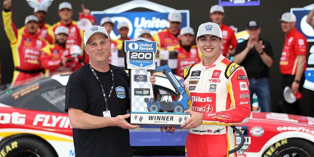 Sammy Smith, driver of the #18 Toyota Pilot Flying J, receives the United Rentals 200 trophy in victory lane after winning the NASCAR Xfinity Series United Rentals 200 at Phoenix Raceway on March 11, 2023 in Avondale, Arizona.