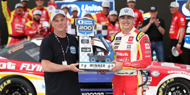 Sammy Smith, driver of the #18 Toyota Pilot Flying J, receives the United Rentals 200 trophy in victory lane after winning the NASCAR Xfinity Series United Rentals 200 at Phoenix Raceway on March 11, 2023 in Avondale, Arizona.