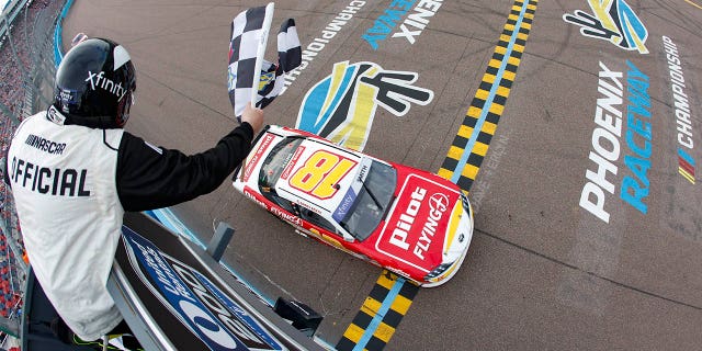 Sammy Smith, pengemudi #18 Pilot Flying J Toyota, mengibarkan bendera kotak-kotak untuk mengibarkan NASCAR Xfinity Series United Rentals 200 di Phoenix Raceway pada 11 Maret 2023 di Avondale, Arizona.
