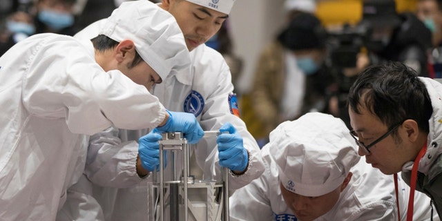 In this Thursday, December 17, 2020 photo provided by Xinhua, technicians prepare to weigh a container carrying lunar samples recovered by China's Chang'e 5 lunar lander in Beijing.