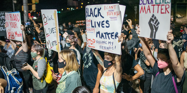 People hold up signs outside Austin Police Department after a vigil for Garrett Foster on July 26, 2020 in downtown Austin, Texas.