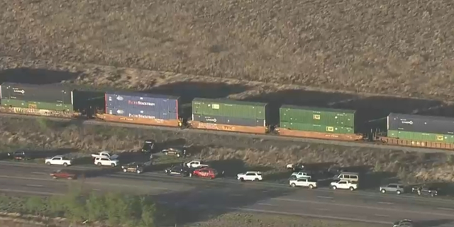 Vehicles and law enforcement officers were photographed by helicopter investigating train cars where more than a dozen migrants were found suffocated near San Antonio, TX.  (Credit: KENS 5 San Antonio)