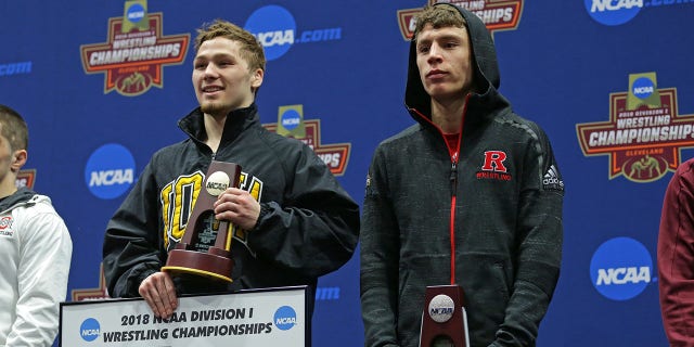 Spencer Lee de los Iowa Hawkeyes y Nick Suriano de los Rutgers Scarlet Knights suben al podio durante la sexta ronda de la NCAA.