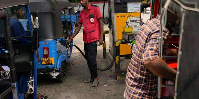 A man fills gas into a vehicle at a fuel station in Colombo, Sri Lanka, on March 29, 2023. Sri Lanka's government announced reduction in fuel prices.