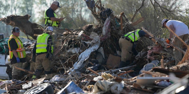 Emergency rescuers and first responders climb through a tornado demolished mobile home park looking for bodies that might be buried in the piles of debris, insulation, and home furnishings on March 25, 2023, in Rolling Fork, Miss.