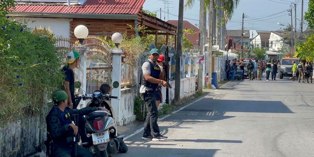 Policemen with guns take positions on a street near the neighborhood of a gunman's house in Phetchaburi province, southwest of Bangkok, Thailand, on March 22, 2023.