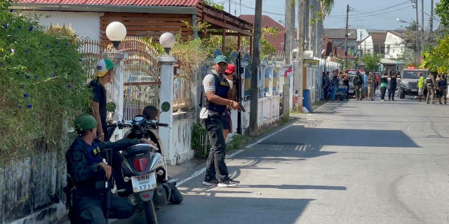 Policemen with guns take positions on a street near the neighborhood of a gunman's house in Phetchaburi province, southwest of Bangkok, Thailand, on March 22, 2023.