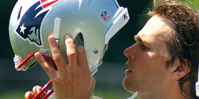 New England Patriots quarterback Tom Brady puts on his helmet during a water break.