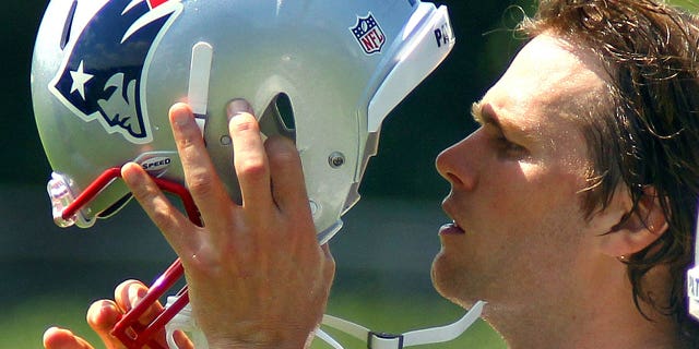 New England Patriots quarterback Tom Brady puts on his helmet during a water break.