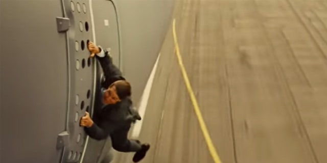 Tom Cruise hanging off the side of a plane in a stunt for Mission Impossible Rogue Nation