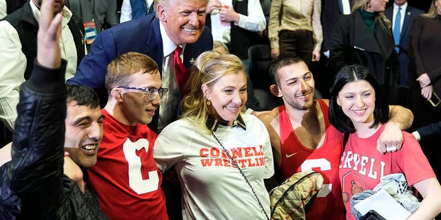 El expresidente Donald Trump posa para una foto con Vito Arujau, segundo desde la derecha, campeón de lucha libre de la NCAA en la categoría de las 133 libras, y su familia en el Campeonato de Lucha Libre de la NCAA, el sábado 18 de marzo de 2023 en Tulsa, Oklahoma.