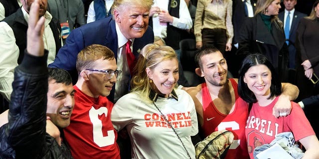 El expresidente Donald Trump posa para una foto con Vito Arujau, segundo desde la derecha, campeón de lucha libre de la NCAA en la categoría de las 133 libras, y su familia en el Campeonato de Lucha Libre de la NCAA, el sábado 18 de marzo de 2023 en Tulsa, Oklahoma.